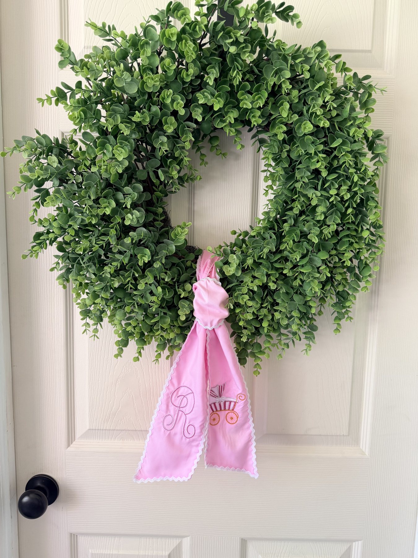 Green wreath with a pink embroidered sash