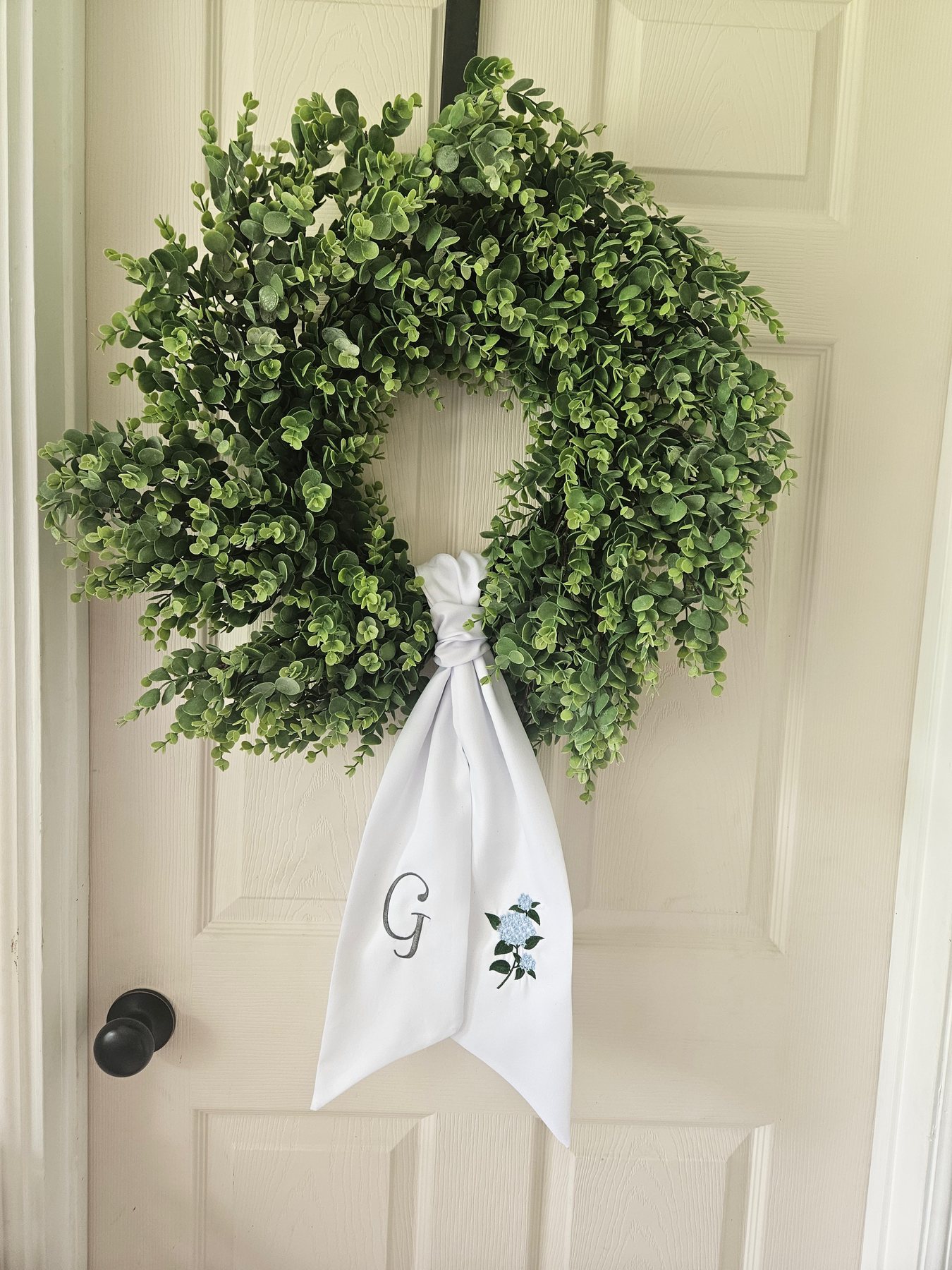 Green wreath with a white embroidered sash
